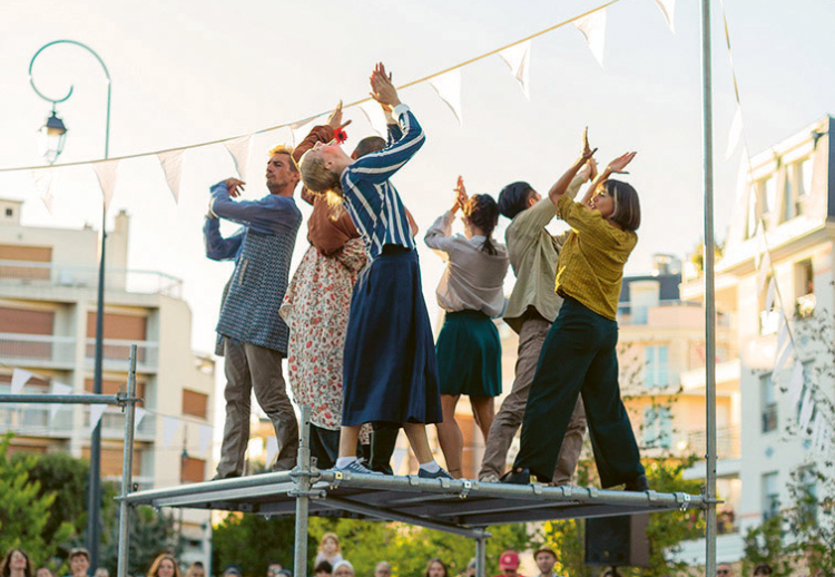 Photo des comédiens de la compagnie Diptik groupé sur un échafaudage et levant les mains au ciel
